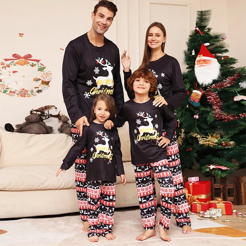 Family wearing matching Christmas pyjamas in front of the tree 